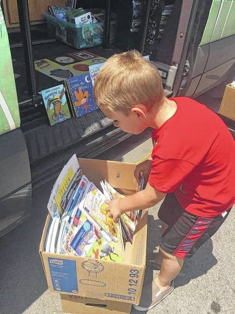 Photo courtesy of Tina Schneider A boy looks through a box filled with books for something that catches his eye.